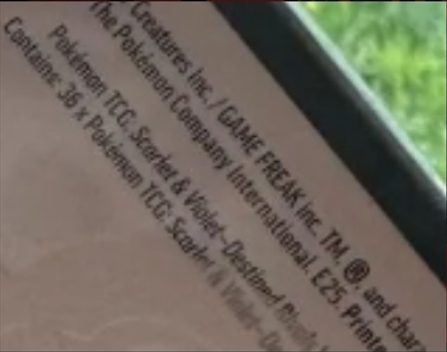 Close-up of copyright text and licensing info on Pokémon Scarlet & Violet Destined Rivals sealed box packaging